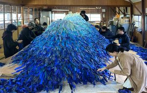 Emilie Faïf, plasticienne, novembre 2025, œuvre « Our Island », Setouchi Triennale 2025, Japon. L’installation est constituée de milliers de languettes de tissus bleus, collectées et nouées par les insulaires et des volontaires. 