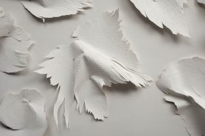 Angèle Guerre, artist, 2018, “Les Mues”. Scalpel-incised paper and studs. Les Mues are mutant forms taken from the work “Tender Text”. They are almost animal skins of paper. When pinned there, they dance.