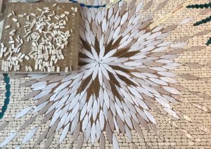 Mathilde Jonquière, mosaïste, Juin 2019, Triptyque Céleste. La mosaïque est composée de tesselles d’or cuivrées riches et profondes et de tons plus neutres (lin, sable, terre d’ombre) symbolisant la trame du fond d’une tapisserie sur laquelle on brode.